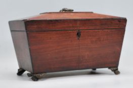 A 19th Century Georgian mahogany tea caddy of sarcophagus form having a brass paw feet and applied