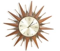 An original retro vintage Metamic starburst teak and brass wall clock with quartz movement. Measures