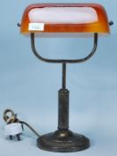 A vintage 20th Century brass bankers lamp having an orange shade with column stem raised on a