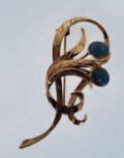 A 20th Century gold plated dress brooch of scrolled leaf form being set with two opal cabochons
