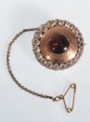 A 19th Century Victorian brooch of round form set with a central red stone cabochon in an engraved