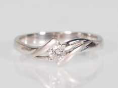 An 18k white gold single solitaire crossover diamond ring set with a central faceted cut round