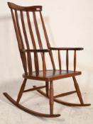 A 20th Century Danish retro vintage dark stained teak wood rocking chair having a tall backrest with