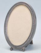 A early 20th Century silver mounted photo frame of oval form with engraved and repousse decoration