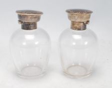 A pair of silver topped dressing table perfume bottles, each lid of round form set with tortoise