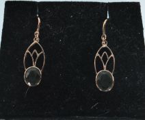 A pair of 9ct gold ladies drop earrings having pierced decoration set with oval cut green peridot