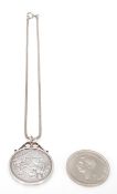 An 1890 Victorian silver crown coin set within a scrolled coin mount on a silver snake chain