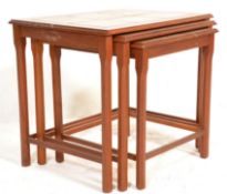 A 1970's Danish influence teak wood and tile top nest of graduating tables being raised on shaped