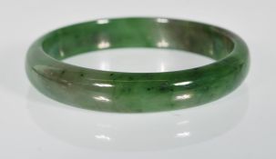 A Chinese green jade slave bangle of round plain form.