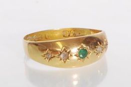 A hallmarked 18ct gold gypsy ring set with a central round cut emerald and fourn round cut diamonds.