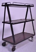 A retro mid century library trolley having black metal a-frames with castors supporting graduating 3