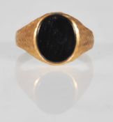 A hallmarked 9ct gold signet ring having an oval black stone panel set to the head with bark