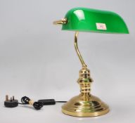 A vintage style bankers desk lamp having an adjustable green glass shade raised on a brass support
