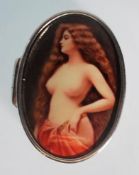 A small silver pill box in an oval shape featuring an enamelled lid. The enamel depicts a female