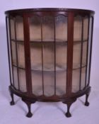 An early 20th Century Edwardian mahogany bow front / demi lune glass display cabinet being raised on
