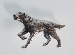 A sterling silver brooch in the shape of a red setter dog wearing a collar and holding one foot