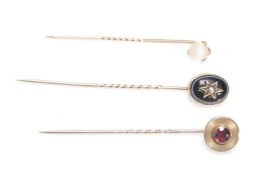A group of three Victorian stick pins to include a pin set with a round cut amethyst in an engine