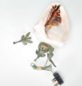 A 20th Century carved conch shell desk top light raised on a cast metal tripod base, the side of the