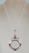 A ladies silver necklace with a silver magnifying glass pendant. Rubies and filigree work