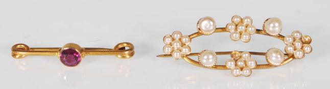 A stamped 9ct gold bar brooch set with a central rounf cut pink stone (measures 3cm wide) together