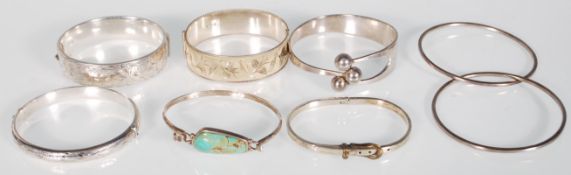 A collection of silver bangles to include a hallmarked sterling silver bangle with etched foliate