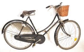 A vintage retro 1970's Raleigh road bike having a black tubular frame with wicker basket to the