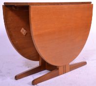 A mid century teak wood drop leaf dining table being raised on splayed legs with half moon shaped
