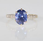 A 9ct yellow gold ladies dress ring set with an oval faceted cut blue stone with illusion set