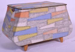 A vintage mid 20th Century ottoman box of angular form, hinged top raised on stub supports, carry