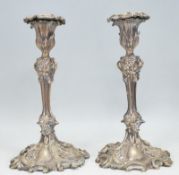 A pair of 20th Century silver plated candlesticks having floral scones to the tops, raised on reeded