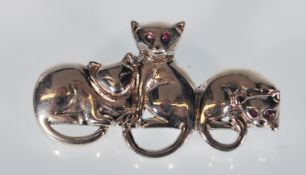 A sterling silver ladies brooch featuring three stylized cats with gemstone eyes. Measures: 4.2cm.