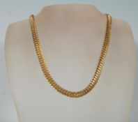 A contemporary gold plated flat fancy link chain necklace having large woven links with a tongue