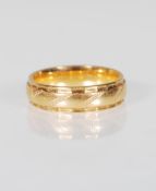 An 18ct gold wedding band ring having engraved twist decoration with faceted borders. Marked 750
