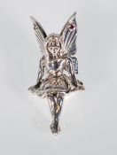 A silver figure of a fairy sitting cross-legged. Red glass detail features at the top of the