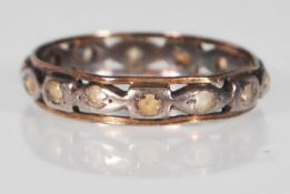 A stamped 9ct gold two tone eternity ring having pierced decoration set with white stones. Stamped