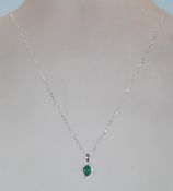 A ladies stamped 18CT white gold chain necklace. An oval emerald is set centrally amidst a halo of