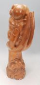 An unusual hardwood carved sculpture depicting face with hand coming out of the mouth and holding