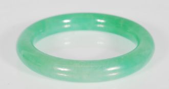 A 20th Century Chinese green jade bangle of round form. Interior diameter 5.5 cm. Measures 7.5 cm