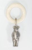 An early 20th Century Edwardian teething ring having a silver plated metal teddy bear charm in the