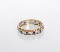 A hallmarked two tone 9ct gold eternity ring set with alternate white and blue stones having faceted