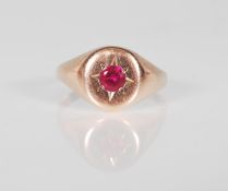 A 9ct rose gold signet ring set with a central round cut red stone with engraved star design