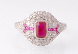 A white metal Art Deco ruby and diamond bombe ring. The ring being set with a central emerald cut