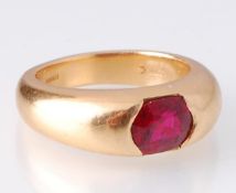A hallmarked 1970's 18ct gold and ruby ring. The ring set with an oval mixed cut ruby within a
