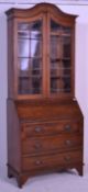 An Edwardian solid oak bureau bookcase raised on s