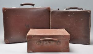 A group of three vintage 20th Century stacking brown leather suitcases having brown leather handles.