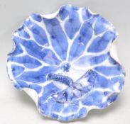 An Oriental blue and white bowl in the form of a lotus leaf with fanned edges having an applied