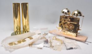 A collection of brass clock parts to include cogs, cylinders, hands, bells etc. likely from a