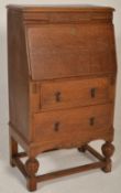 A 1920s Art Deco oak bureau decorated with a floral pediment top set over a fall front writing
