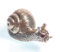 A stamped sterling silver figurine / miniature box in the form of a snail having red stone eyes, the