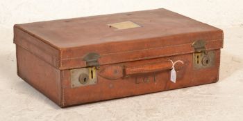 A good quality early 20th century leather suitcase with clasp locks and leather handles, remains